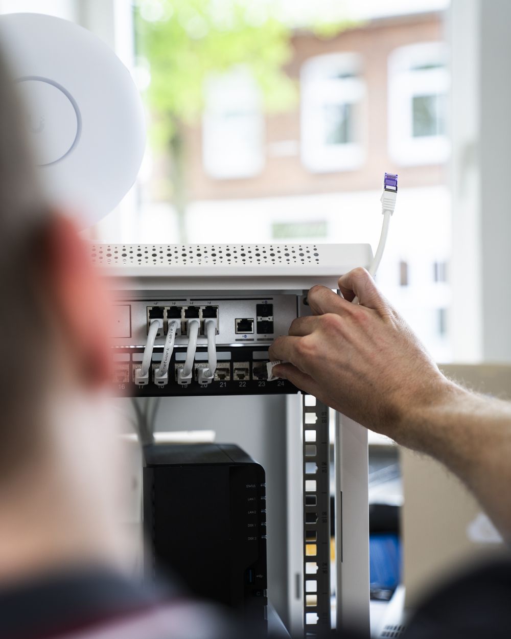 Conto-IT-Techniker patcht Netzwerkkabel im Serverschrank
